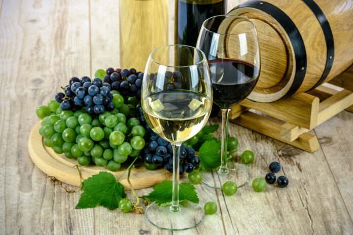 lokalec-photo-7 Simbolična fotografija kozarcev belega in rdečega vina z grozdjem ob lesenem sodu