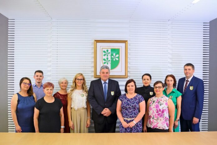 Skupinska fotografija pred grbom Občine Kidričevo