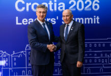 Janša na MED9 izpostavil demografijo: predlog za prihodnji vrh Janez Janša in Andrej Plenković se rokujeta, v ozadju so panoji s simboli Vrha MED9.